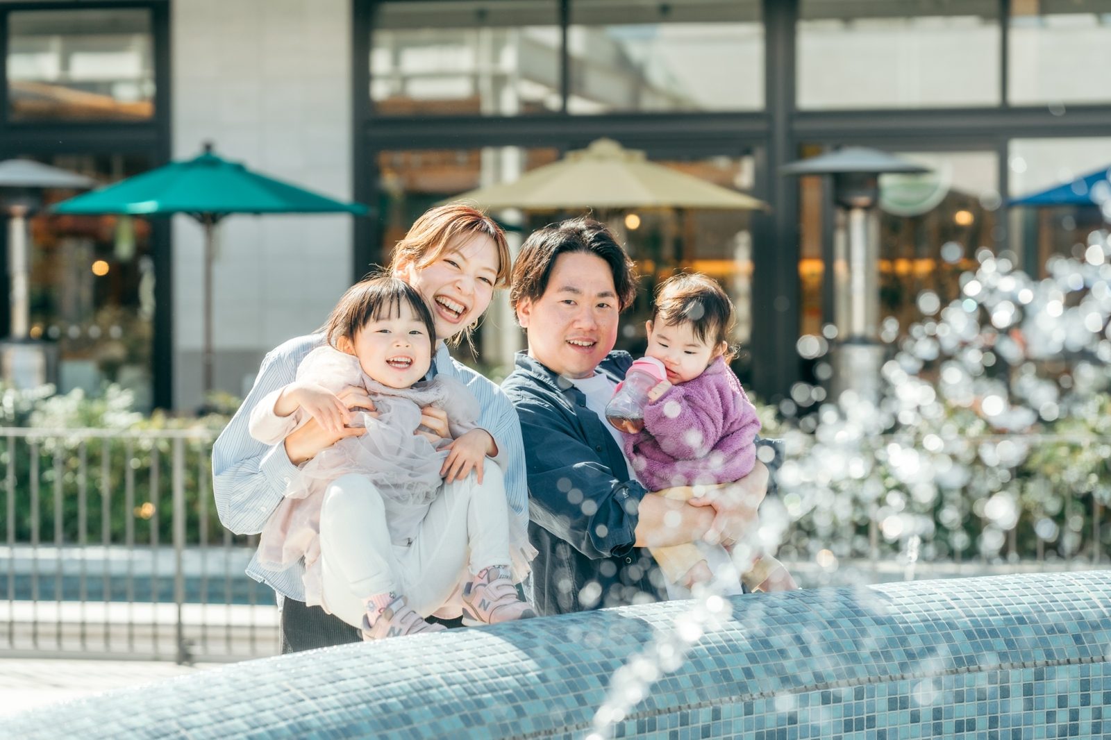 噴水前で笑顔の親子4人。And Familyに集う家族の様子
